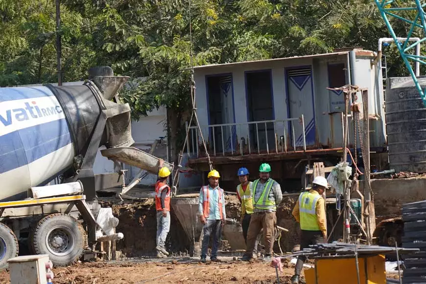 Workers stand by a cement mixer carrying RMC for diaphragm wall construction