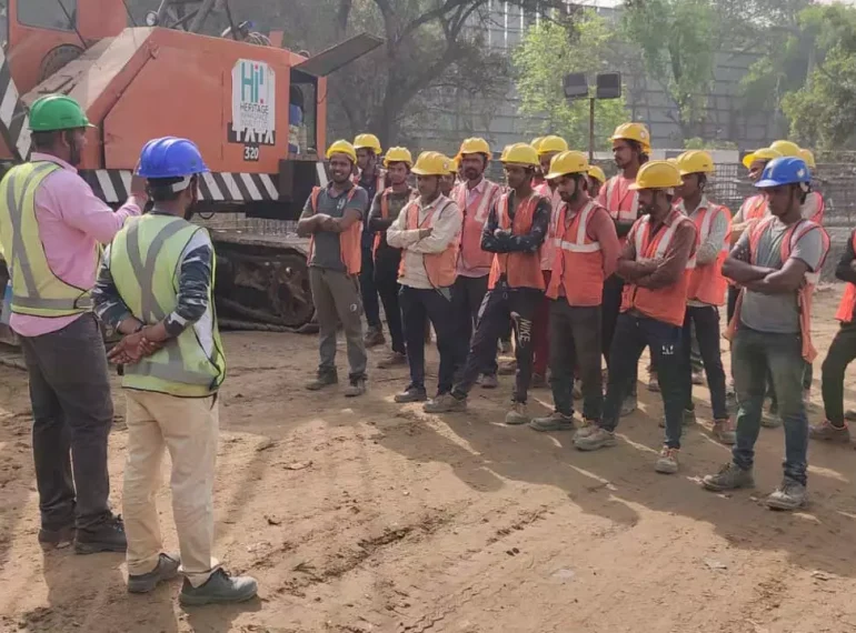 A safety supervisor on a construction site briefs a team of workers