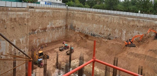 Workers use machinery to construct a deep diaphragm wall for a large hole on a construction site