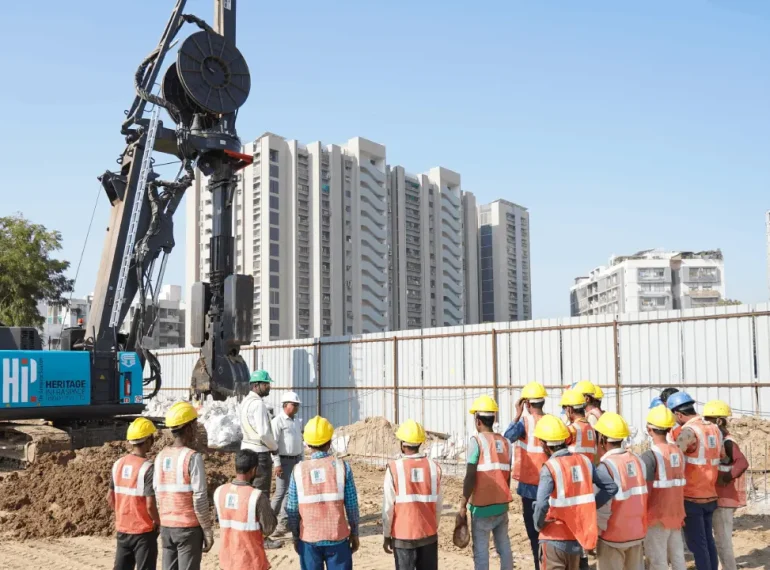 A group of workers stand next to a hydraulic rig for diaphragm wall construction